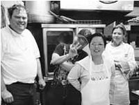 Clients at The Arc San Francisco standing in an institutional kitchend with aprons , Chef Allison is in the background