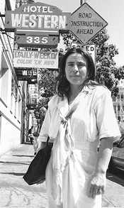social worker with briefcase standing under the sigh of a SRO hotel