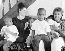 Amy Dooha-Chambers sitting on a couch with  4 kids and Paula McMurray the adoptive mother