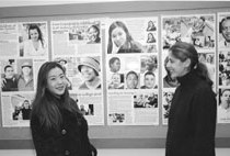 Christine Lou and Sonia Reshid discussing the social worker photo exhibit in the background