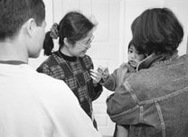 Social worker admiring a young child.  The mother is holding the child and the father looks on.