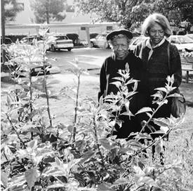 Jackson helping her mother walk, they are looking at flowers