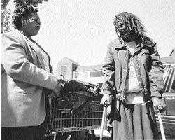 Eva standing next to Pharaoh, who is on crutches next to his shoping cart filed with belongings.