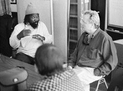 a group of people sitting around a table, while Wayne tells a stroy. Leland listens.