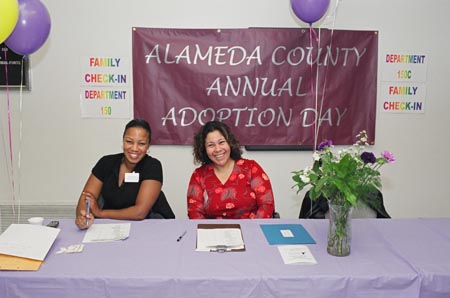 Two adoption workers sitting at a welcome table